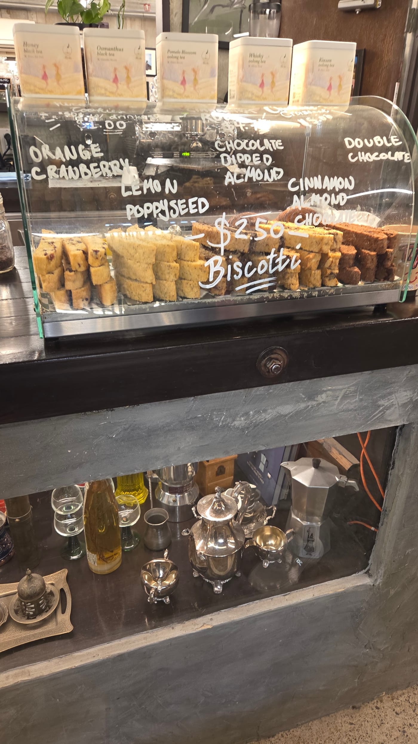 Biscotti in the counter case, tea tins on the shelf above